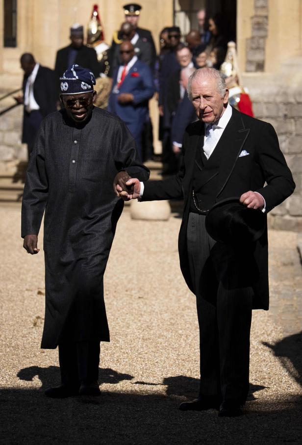Bola Ahmed Tinubu und König Charles halten sich an den Händen.