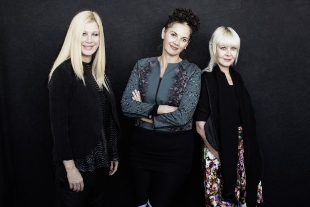 Drei Frauen posieren vor einem schwarzen Hintergrund.