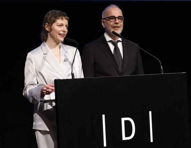 Zwei Personen im Anzug stehen nebeneinander an einem Rednerpult mit Mikrofonen und sprechen.