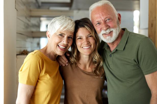 Portrait of happy senior parents and their adult daughter at home.