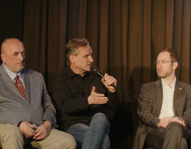 Drei Männer sitzen nebeneinander