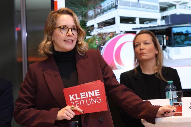 Zwei Frauen bei einer Podiumsdiskussion, eine hält Karten mit der Aufschrift „Kleine Zeitung“.