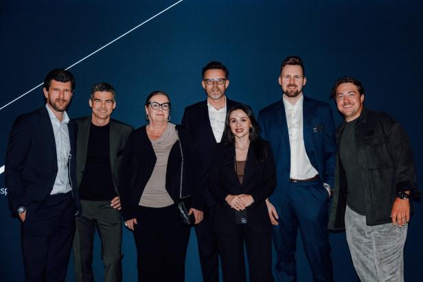 Mehrere Personen posieren vor einer Kia-Leinwand.