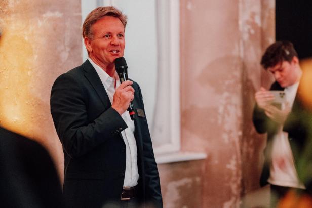 Mann im Anzug hält ein Mikrofon und spricht auf dem Kia-Event.