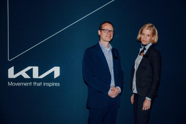 Zwei Personen posieren vor einer Kia-Leinwand.
