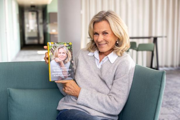 Eine Frau präsentiert lächelnd ihr Buch "Der Zitronenbaum in meinem Garten".
