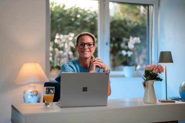 Eine Frau in einem Kittel sitzt hinter einem Laptop 