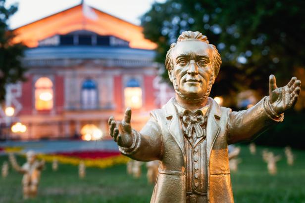 Eine goldene Statue vor einem Opernhaus 