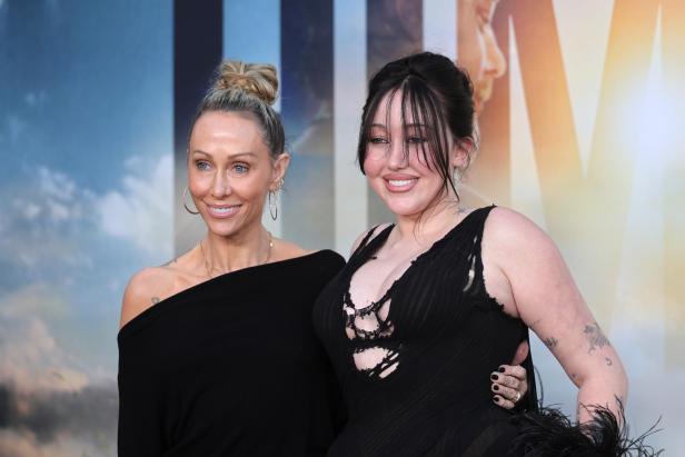 Noah Cyrus posiert mit ihrer Mutter Tish Cyrus auf dem roten Teppich, beide lächeln und tragen schwarze Outfits.