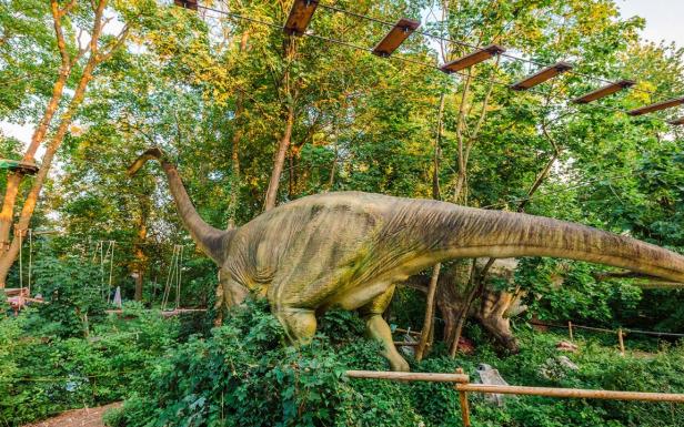 Das Brachiosaurus-Modell steht zwischen Büschen und Bäumen.