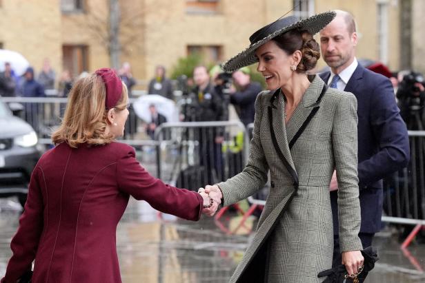 Kate schüttelt die Hand einer Frau, während Prinz William im Hintergrund steht.