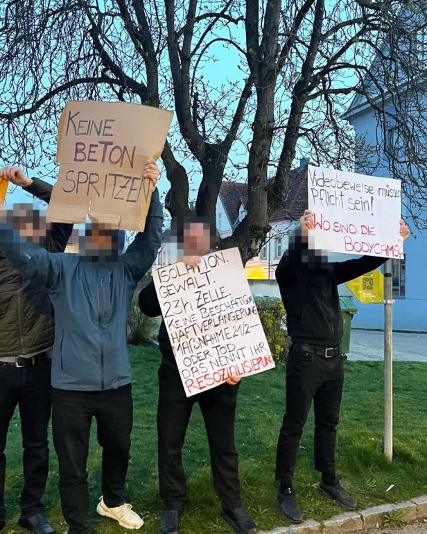 Mehrere Personen halten Schilder und protestieren damit vor dem Gefängnis.