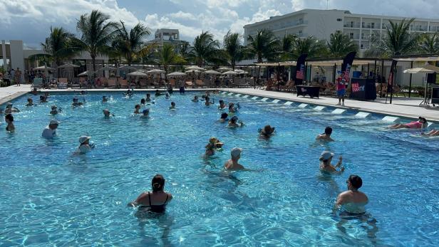 Eine Gruppe von Menschen nimmt an Wassergymnastik in einem Pool im Freien teil.