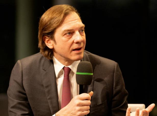 Ein Mann im Anzug mit einem Mikro 