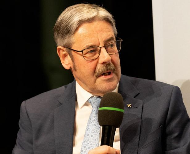 Ein Mann im Anzug spricht mit einem Mikrofon während einer Podiumsdiskussion.