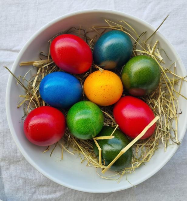 Bunte Ostereier in einer Schüssel auf Heu gebettet. 
