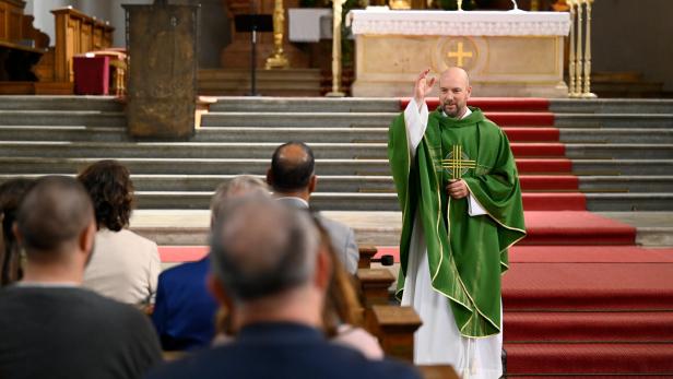 In einer Kirche segnet Pfarrer Reiser in grünem Umhang die Gemeinde.