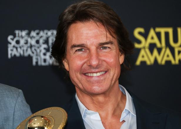 Tom Cruise lächelt vor einem Hintergrund der Saturn Awards.