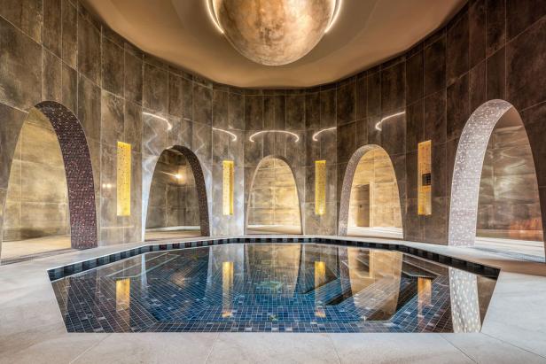 Achteckiger Indoor-Pool mit Mosaikfliesen und gewölbten Durchgängen in luxuriösem Spa-Bereich.