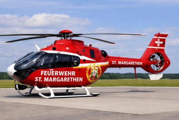 Roter Feuerwehr-Hubschrauber mit der Aufschrift „FEUERWEHR ST. MARGARETHEN“ steht auf einem Flugplatz.