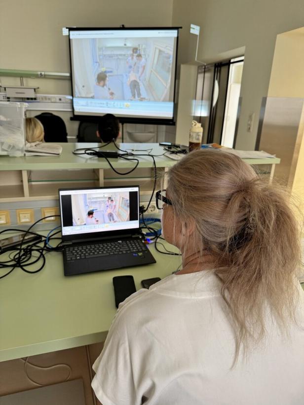 Eine Frau betrachtet am Laptop eine medizinische Schulung, die gleichzeitig auf eine Leinwand projiziert wird.