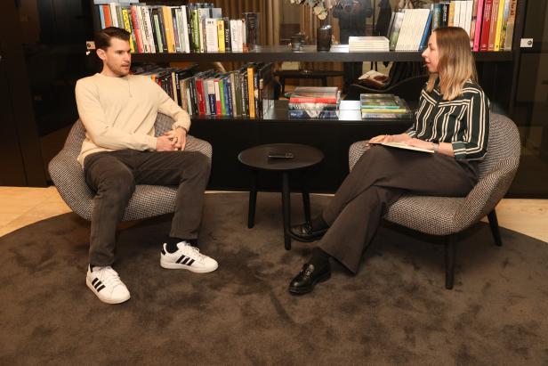 Zwei Personen sitzen in Sesseln vor einem Bücherregal und unterhalten sich.