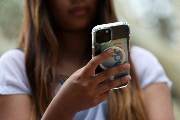 Eine Person mit langen Haaren hält ein Smartphone mit transparentem Case in der Hand.