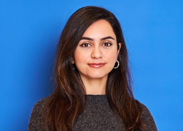 Die deutsche Iran-Expertin Diba Mirzaei steht vor blauem Hintergrund.