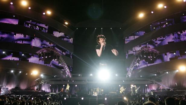 Mick Jagger tritt mit den Rolling Stones auf einer beleuchteten Bühne auf.