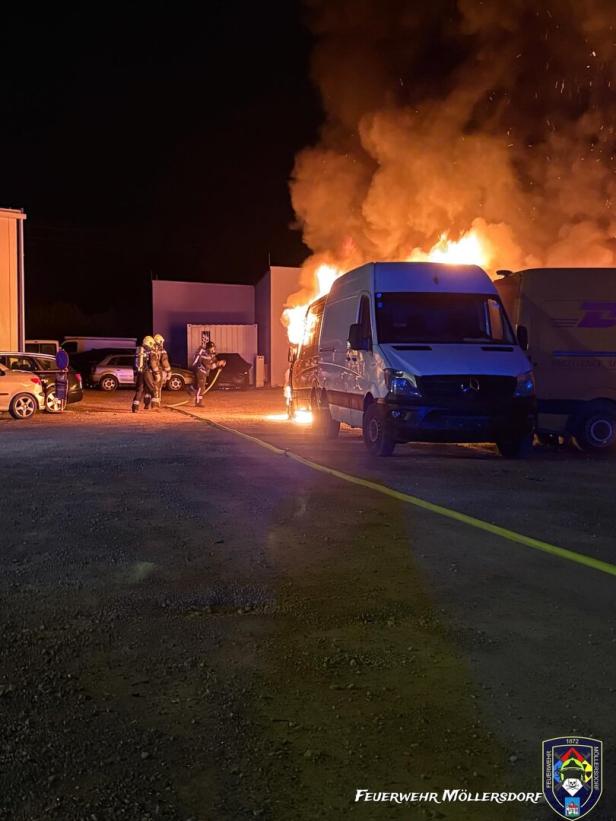 Ein Lieferwagen steht in Flammen, während Feuerwehrleute in Schutzkleidung den Brand bekämpfen.
