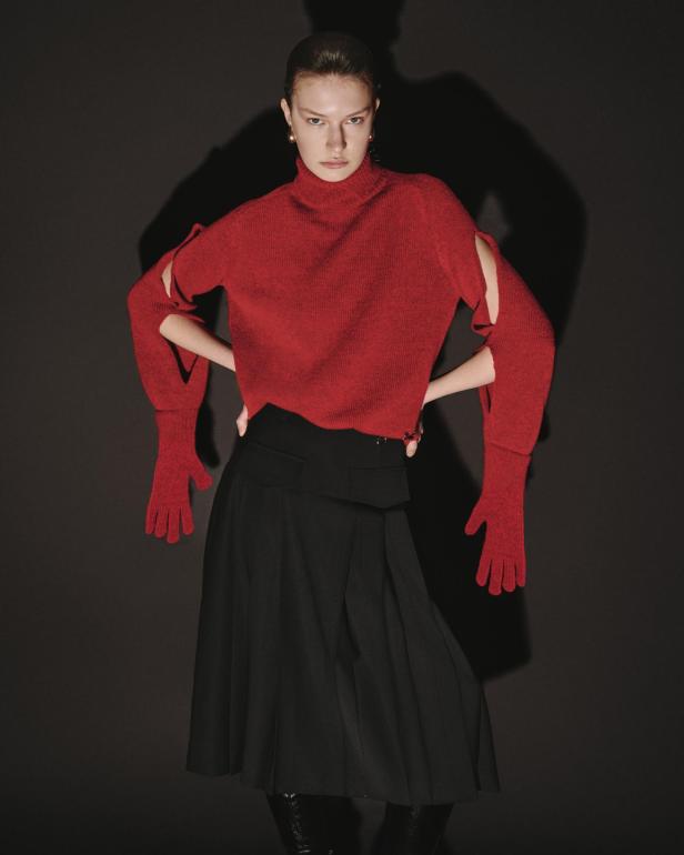 Ein Model in rotem Pullover und schwarzem Rock