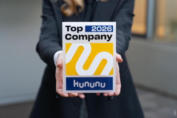 Eine Person hält eine Auszeichnung mit der Aufschrift „Top Company 2026 kununu“, die das MCI als attraktiven Arbeitgeber hervorhebt.