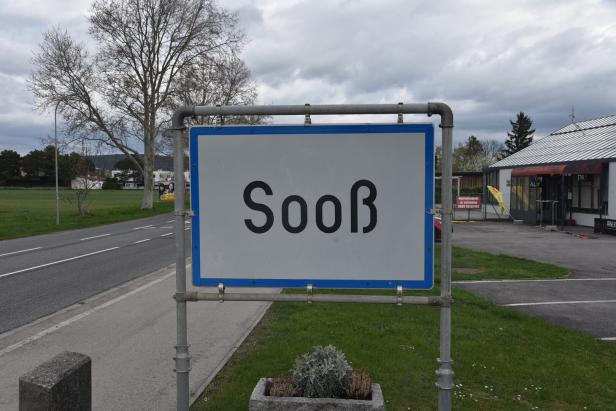 Ein Ortsschild mit der Aufschrift "Sooß" steht am Straßenrand.