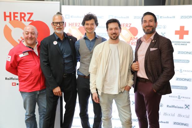 Fünf Personen stehen vor einer Rotkreuz-Wand