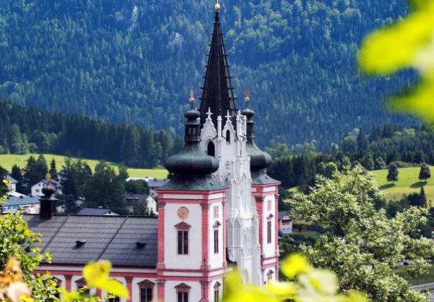 Basilika Mariazell mit markanten Türmen vor bewaldeter Berglandschaft im Sommer.