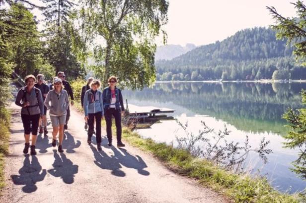 Eine Gruppe von Wanderern geht auf einem Weg entlang eines Sees.