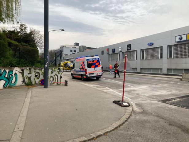 Ein Rettungswagen, Einsatzkräfte und ein gelandeter Rettungshubschrauber stehen vor einer Baustelle in der Muthgasse in Wien-Döbling.
