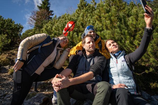 Vier Personen machen während einer Wanderung gemeinsam ein Selfie im Grünen.