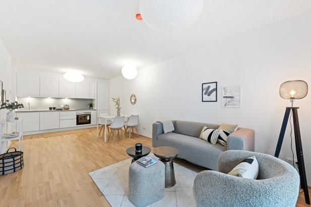 Modern eingerichteter Wohnraum mit offener Küche, Essbereich und gemütlicher Sitzecke im Neubauprojekt Ameisgasse 28 in Wien-Penzing.