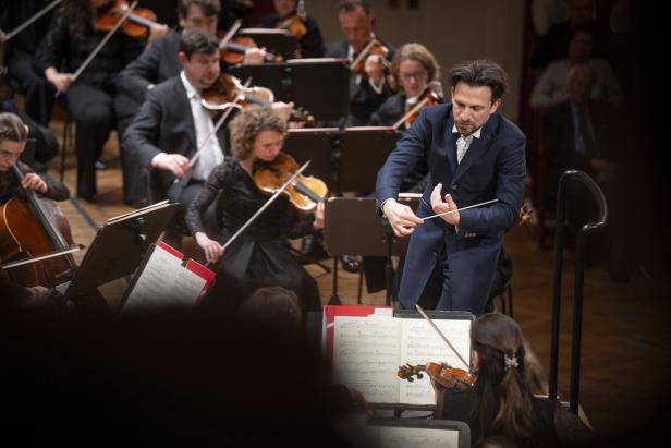 Dirigent Meister leitet ein Orchester mit Geigen und Celli.