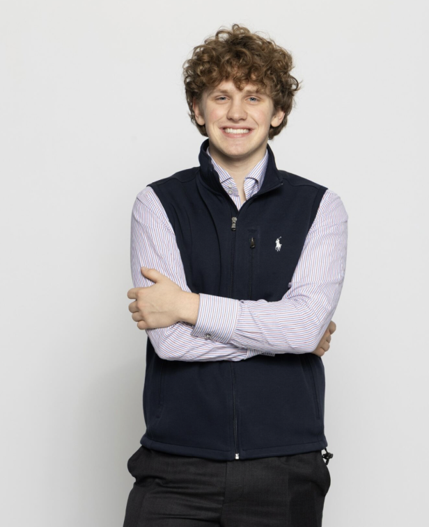 Viktor Lisowski steht vor einem weißen Hintergrund mit verschränkten Armen. Er lächelt.