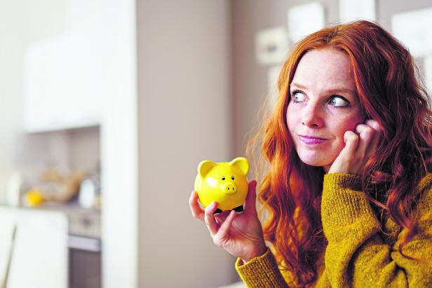 nachdenkliche junge Frau mit Sparschwein