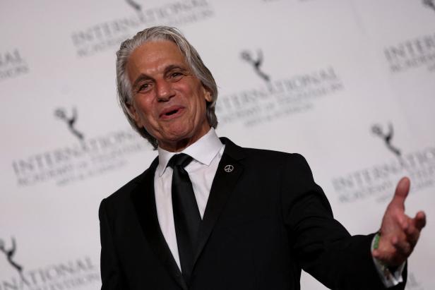 Tony Danza, im schwarzen Anzug mit Friedenssymbol, gestikuliert vor einem Hintergrund der International Academy of Television Arts & Sciences.