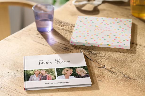 Ein Fotobuch neben einem Glas auf einem Tisch 