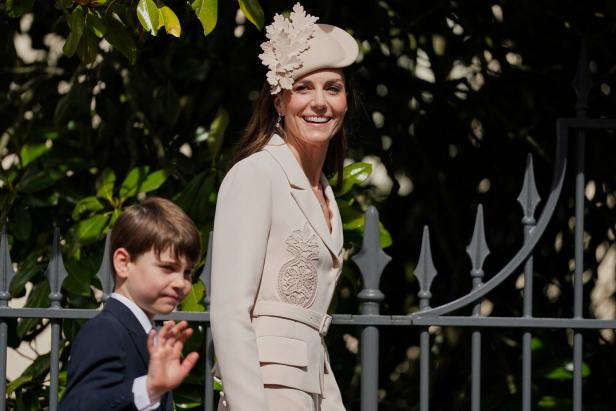 Prinzessin Kate lächelt mit Hut und beigem Blazer, während Prinz Louis winkt.