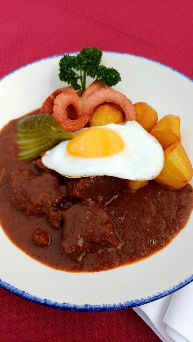 Das klassische Herrengulasch angerichtet auf einem weißen Teller.  