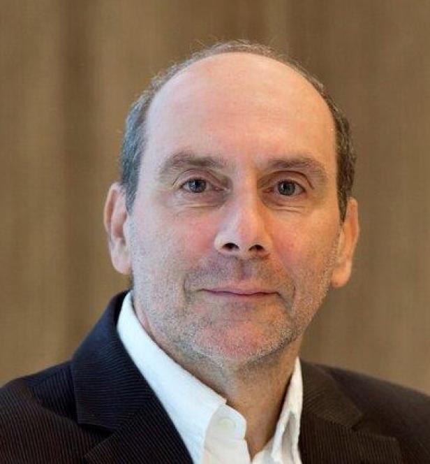 Ein Mann mit Anzug und Hemd blickt in die Kamera.