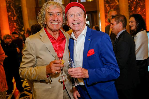 Tony Rei und Heribert Kasper lachen mit Sektgläsern in der Hand.