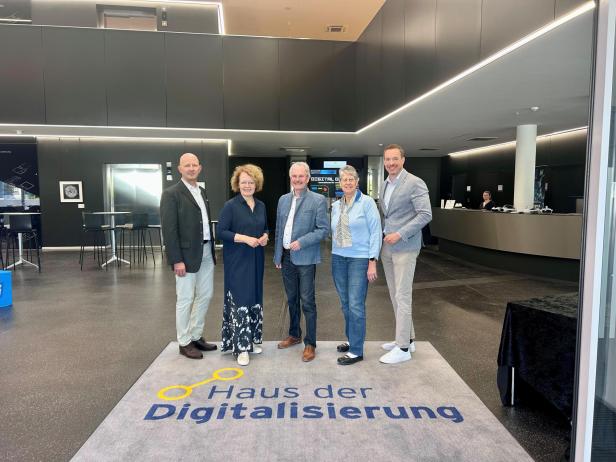 5 Personen stehen im Haus der Digitalisierung in Tulln, auf einem Teppich, der die Aufschrift "Haus der Digitalisierung" trägt.