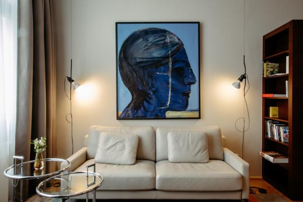 Weiße Couch, dahinter ein Bild mit einem blauen Kopf